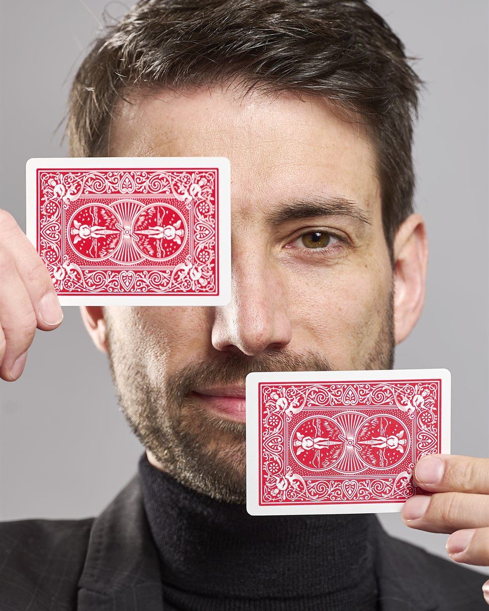 Portrait von Zauberkünstler und Mentalist Oliver Henke mit zwei Spielkarten